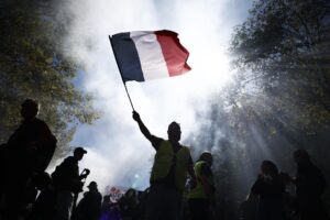 Un hombre agita una bandera francesa este jueves durante las protestas contra las medidas de austeridad en París. EFE/EPA/YOAN VALAT