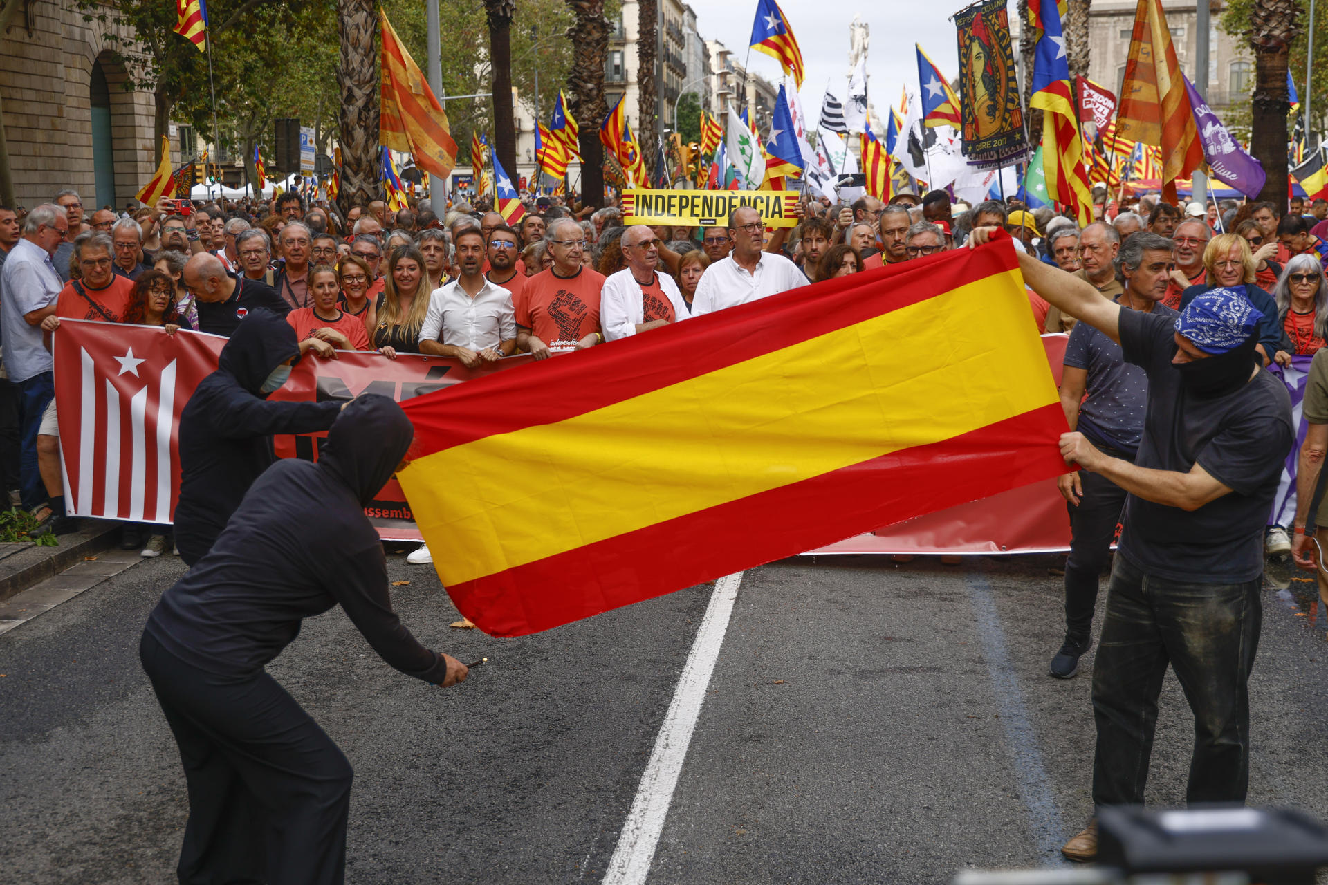 Varias personas despliegan y queman una bandera de España durante la manifestación independentista con motivo de la Diada, este jueves en Barcelona.-EFE/ Quique García
