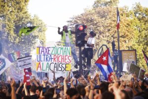París.- Un manifestante enarbola un cartel que dice "Tasa Zucman, los ultrarricos que paguen" durante una manifestación contra las medidas de austeridad que el próximo Gobierno francés pueda incluir en su proyecto de presupuestos para 2026. Francia vivió este jueves una huelga general con protestas por todo el país, en las que hubo cientos de miles de participantes. El último balance de las protestas es de 309 arrestos y 29 heridos . EFE/EPA/Yoan Valat