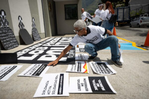 Un hombre organiza carteles durante una concentración por los presos políticos este lunes, frente a la sede de la embajada de España en Caracas (Venezuela). EFE/ Ronald Pena R