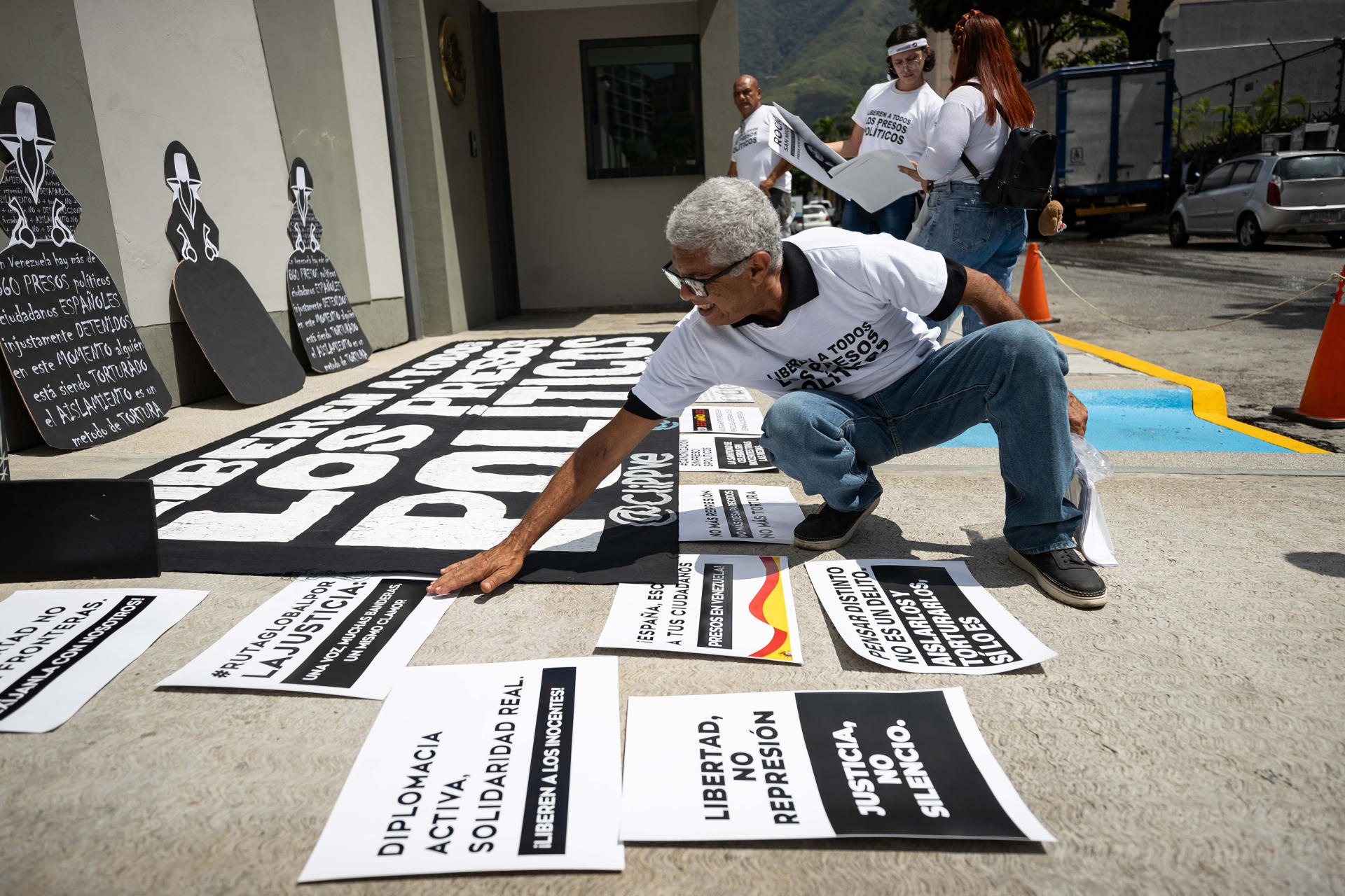 Un hombre organiza carteles durante una concentración por los presos políticos este lunes, frente a la sede de la embajada de España en Caracas (Venezuela). EFE/ Ronald Pena R