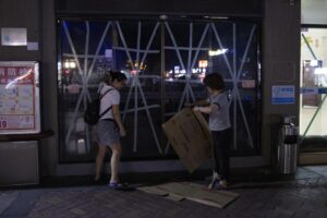 Dos mujeres usan pedazos de cartón para proteger las puertas de vidrio selladas con cinta adhesiva de un restaurante, como parte de los preparativos ante la llegada del tifón Ragasa, en Yangjiang, provincia de Cantón (Guangdong). EFEANDRES MARTINEZ CASARES