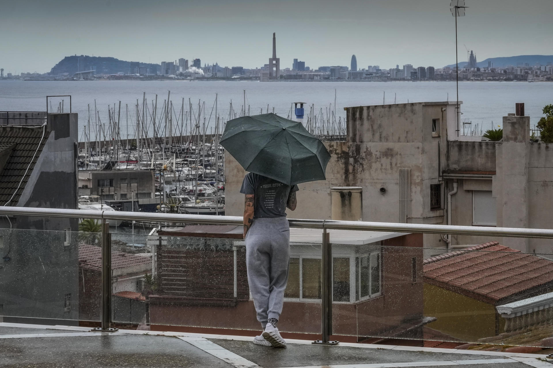 Imagen de julio pasado de una persona observando Barcelona bajo un paraguas. EFE/Enric Fontcuberta