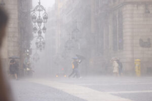 Personas se protegen de la lluvia este jueves en el centro de Barcelona. EFE/ Quique García