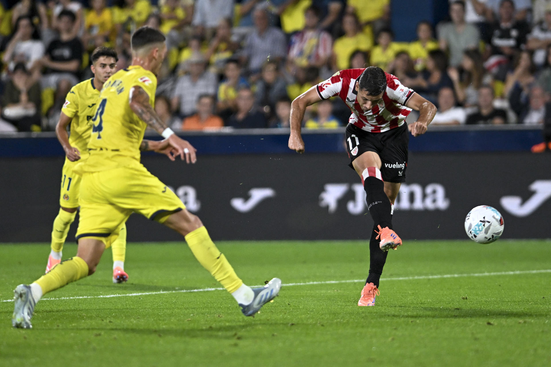 El delantero del Athletic Club, Gorka Guruzeta (d), golpea el balón durante el encuentro correspondiente a la jornada 7 de Laliga EA Sports que disputan hoy sábado Villarreal y Athletic Club en el estadio de La Cerámica, en la localidad castellonense. EFE / Andreu Esteban.
