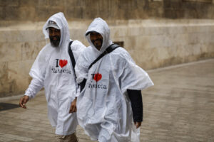 Dos personas pasean bajo la lluvia protegidos con chubasqueros. EFE/Biel Aliño