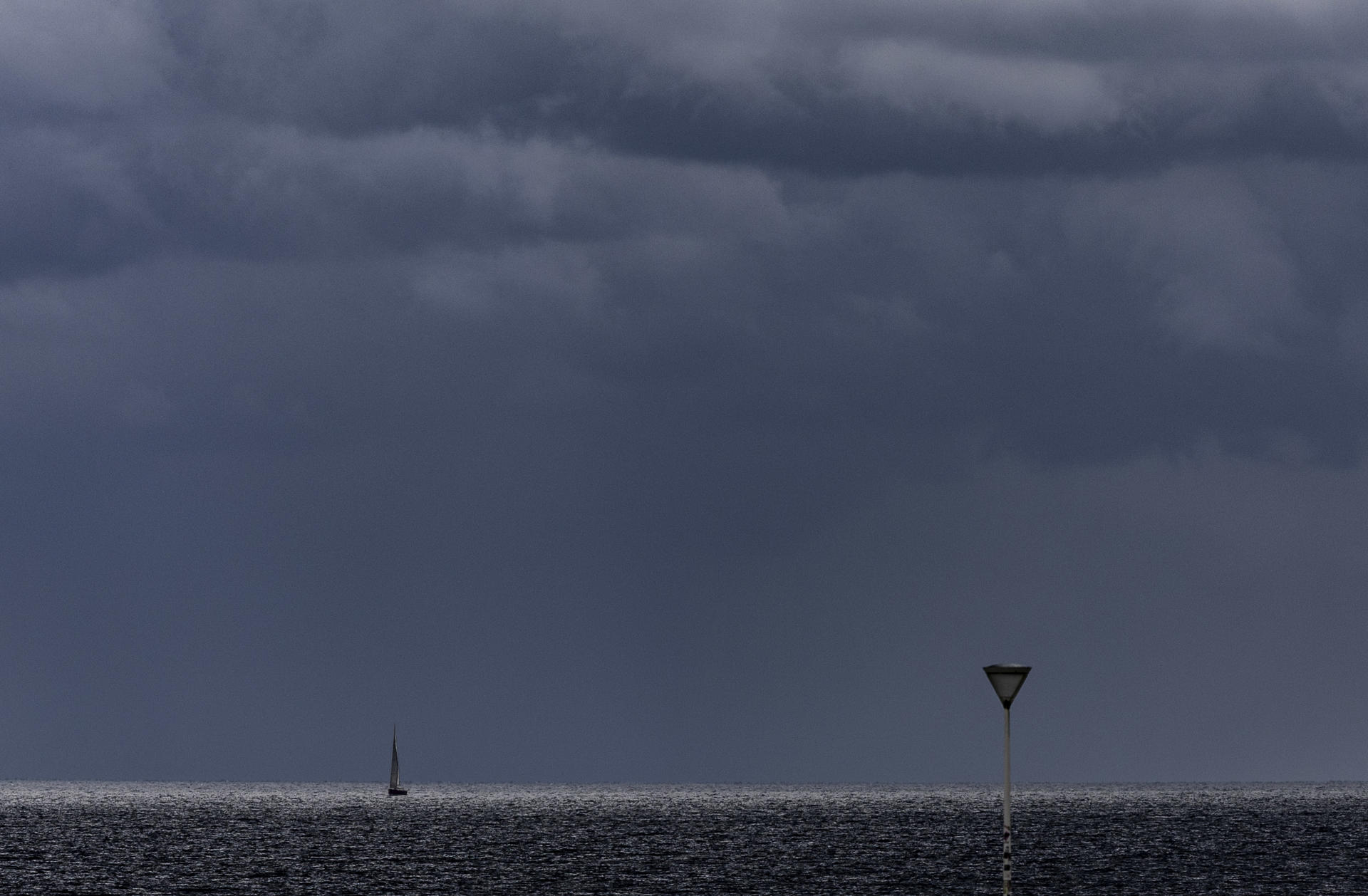 Un pequeño velero navega este jueves junto a la playa de La Zurriola de San Sebastián. EFE/Javier Etxezarreta