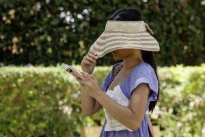 Una mujer se tapa con un sombrero la cara para resguardarse del sol mientras camina por un parque en Sevilla en una imagen de archivo. EFE /José Manuel Vidal