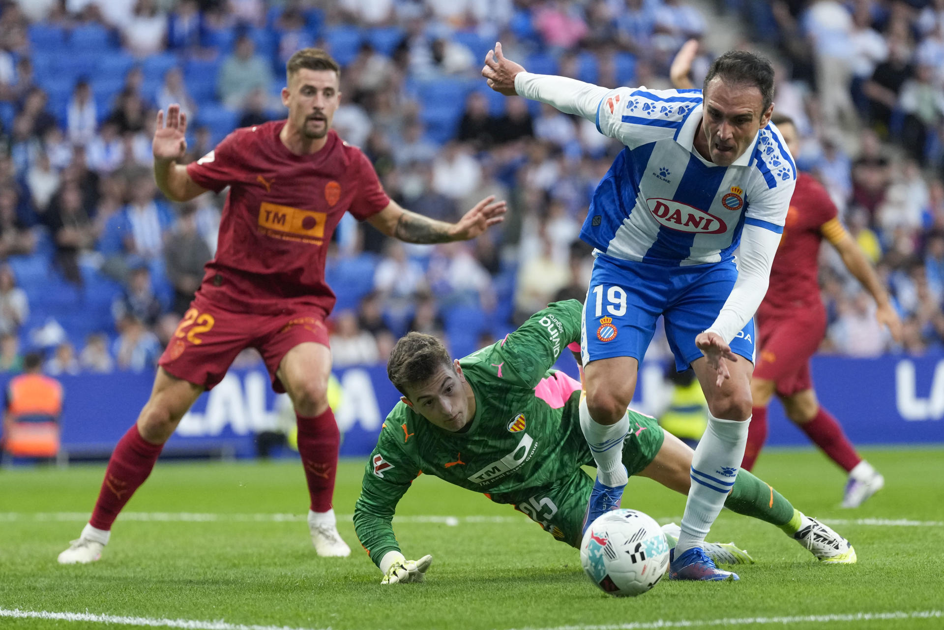El delantero del Espanyol Kike García (d) ante el portero del Valencia Julen Agirrezabala (2i) durante el encuentro correspondiente a la sexta jornada de LaLiga EA Sports disputado entre el RCD Espanyol y el Valencia CF en el RCDE Stadium en Barcelona, este martes. EFE/ Enric Fontcuberta
