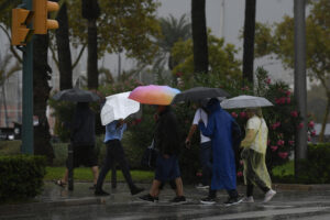 Varias personas se protegen de la lluvia en Palma de Mallorca, donde este martes ha llegado un temporal de lluvia y viento.- EFE/Miquel A. Borrás