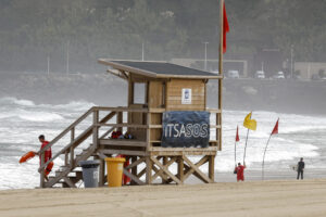 Unos socorristas señalizan la zona de baño este lunes en la playa de la Zurriola de San Sebastián. EFE/Juan Herrero