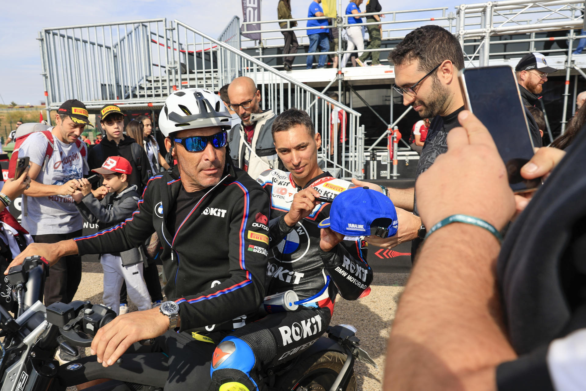 El piloto turco Toprak Razgatlioglu (ROKiT BMW Motorrad WorldSBK Team) firma la gorra de un aficionados tras la carrrera de la Tissot Superpole de SBK del Campeonato del Mundo de Superbikes que se celebra en el circuito turolense de Motorland Alcañiz. EFE/Javier Cebollada