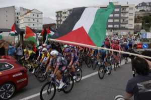 Los ciclistas pasan ante las protestas propalestina durante la etapa 16 de la Vuelta Ciclista a España que se disputa este martes entre Poio y Mos-Castro de Herville (Pontevedra), de 167.9 km de recorrido. EFE/ Lavandeira Jr