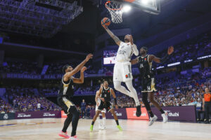 El alero estadounidense del Real Madrid Chuma Okeke (c) entra a canasta ante dos rivales del Asvel durante el partido de la tercera jornada de la temporada regular de la Euroliga que disputan este jueves en el Movistar Arena de Madrid. EFE/Juanjo Martín