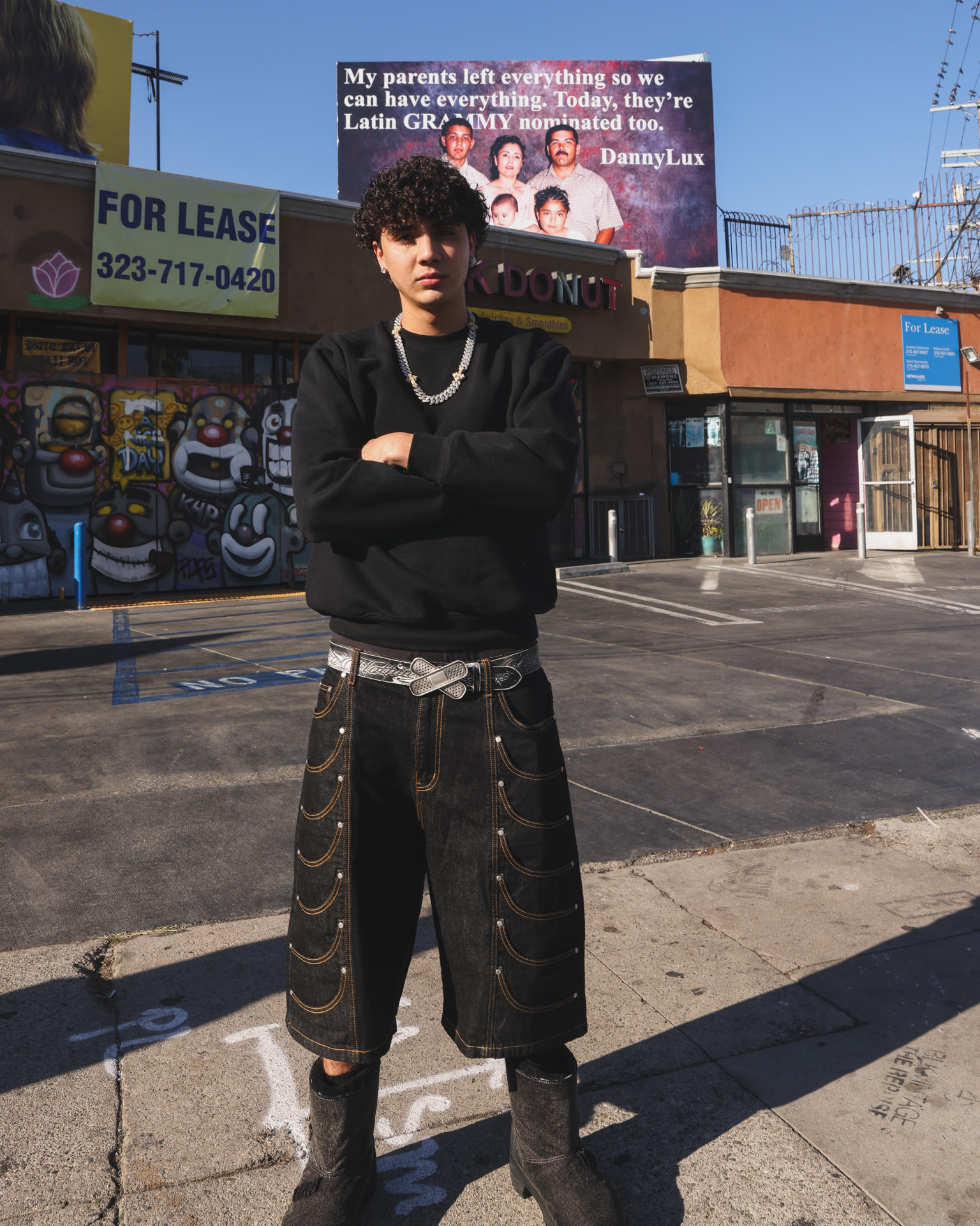 Fotografía cedida por John Choi donde aparece el cantante DannyLux posando frente a una valla publicitaria con la imagen de su familia, este miércoles en Los Ángeles (Estados Unidos). EFE/ John Choi