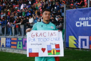 El portero de la selección sub-20 de Nueva Caledonia, Noa Yohan Bernard Bochet Muller, enseña el 5 de octubre un cartel en el que la plantilla expresa su gratitud con el público chlleno durante el torneo. EFE/ Benjamín Hernández