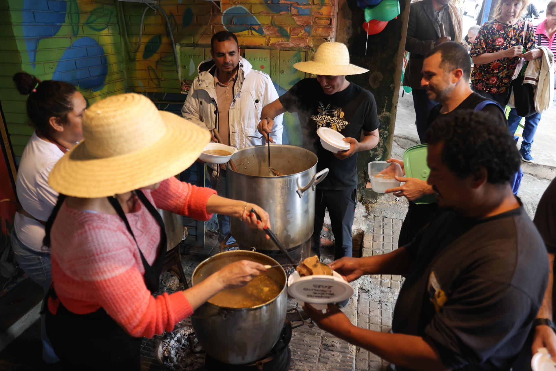 Personas reciben una sopa de vegetales, frijoles y maíz, durante la celebración del jopará este miércoles, en el Mercado 4 en Asunción (Paraguay). EFE/ Juan Pablo Pino
