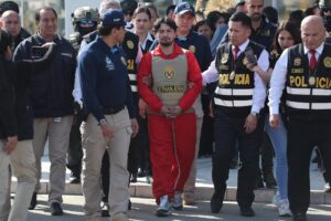 Matías Agustín Ozorio (c), de nacionalidad argentina, es trasladado por integrantes de la Policía Nacional de Perú (PNP) y de Interpol para ser entregado a la Policía Argentina este jueves, en la Base Aérea de Policía Aérea de Perú en Lima (Perú). EFE/ Paolo Aguilar