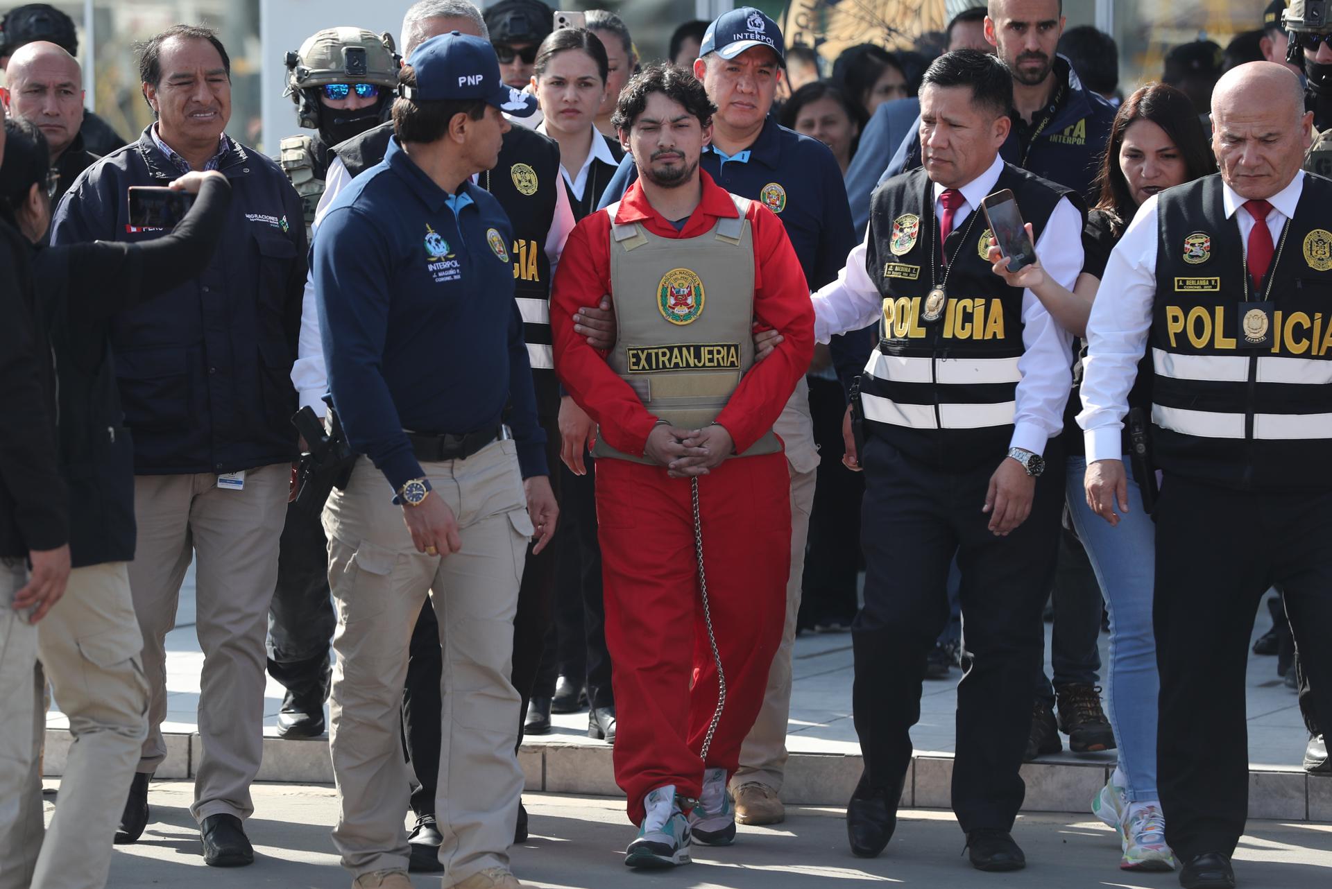 Matías Agustín Ozorio (c), de nacionalidad argentina, es trasladado por integrantes de la Policía Nacional de Perú (PNP) y de Interpol para ser entregado a la Policía Argentina este jueves, en la Base Aérea de Policía Aérea de Perú en Lima (Perú). EFE/ Paolo Aguilar