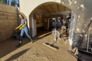 Vecinos retiran barro de sus casas en el área Santa Fe en Zaragoza donde ya han comenzado las tareas de limpieza, este martes, después de las fuertes lluvias registradas en la tarde-noche del domingo. EFE/ Javier Cebollada