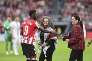 El delantero del Athletic Club Iñaki Williams, saluda a dos mujeres palestinas, durante el partido de la jornada 8 de LaLiga EA Sports entre el Athletic Club y el Mallorca, este sábado en el estadio de San Mamés en Bilbao.-EFE/ Luis Tejido