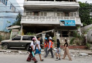 CEBU (Philippines), 02/10/2025.- Personnel from the Department of Science and Technology-Philippine Institute of Volcanology and Seismology (C), who are recording evidences of structural damage and geological impact from an earthquake, walk past a damaged building in Bogo City, Cebu, Philippines 02 October 2025. The death toll from a magnitude 6.9 earthquake that struck off the coast of Cebu island has reached 72, according to the National Disaster Risk Reduction and Management Council (NDRRMC). (Terremoto/sismo, Filipinas) EFE/EPA/ROLEX DELA PENA