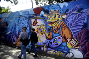 Personas caminan cerca a un mural de una rana dorada este viernes, en Ciudad de Panamá (Panamá). EFE/ Carlos Lemos