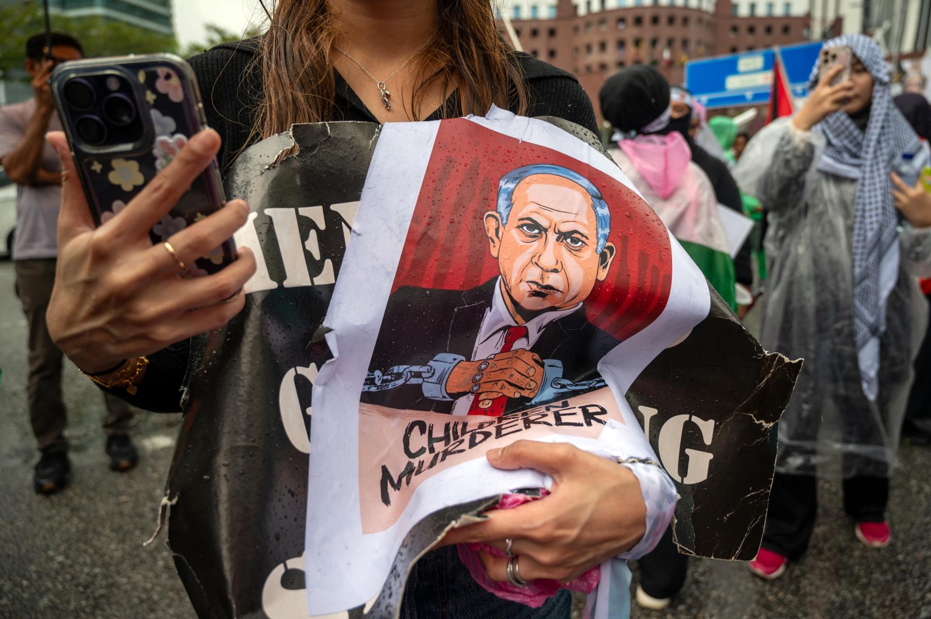 Kuala Lumpur (Malaysia), 03/10/2025.- A protester holds a placard with a caricature of Israeli Prime Minister Benjamin Netanyahu during a demonstration against the Israeli forces' interception of vessels from the Global Sumud Flotilla (GSF) and the detention of Malaysian activists, outside the US Embassy in Kuala Lumpur, Malaysia, 03 October 2025. Israel's interception of the flotilla, which was carrying aid supplies to Gaza Strip, and the detention of all those on board, including at least 23 Malaysian activists, has sparked international condemnation and protests. (Protestas, Malasia) EFE/EPA/NAZIR SUFARI
