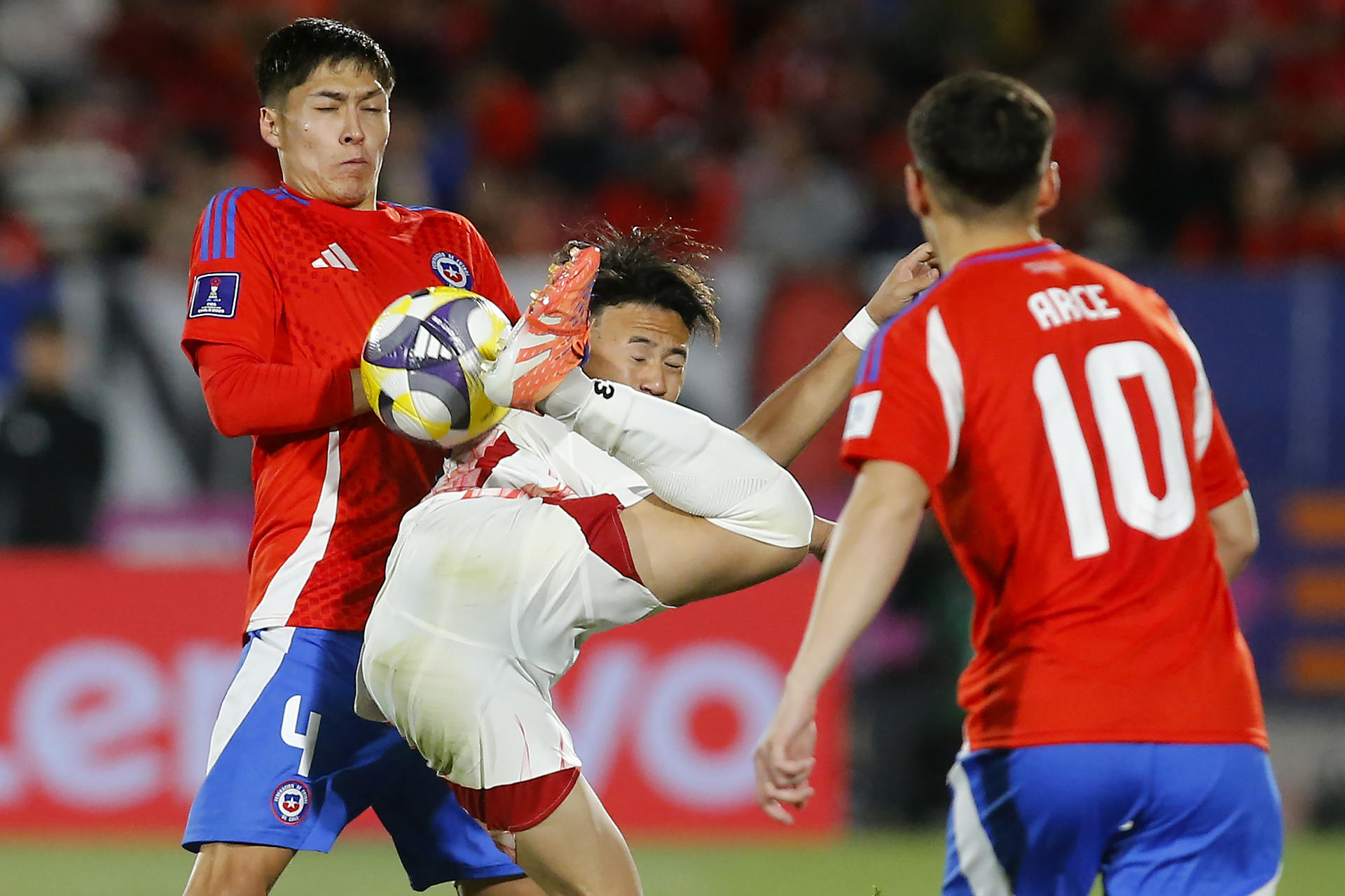 El defensor chileno Patricio Andres Romero (i) neutraliza la maniobra del japonés Kazunari Kita (c) durante el partido del Mundial sub-20 jugado este martes en Santiago. EFE/ Esteban Garay
