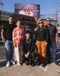 Fotografía cedida por John Choi donde aparece el cantante DannyLux (c) posando frente a una valla publicitaria con la imagen de su familia, este miércoles en Los Ángeles (Estados Unidos). EFE/ John Choi