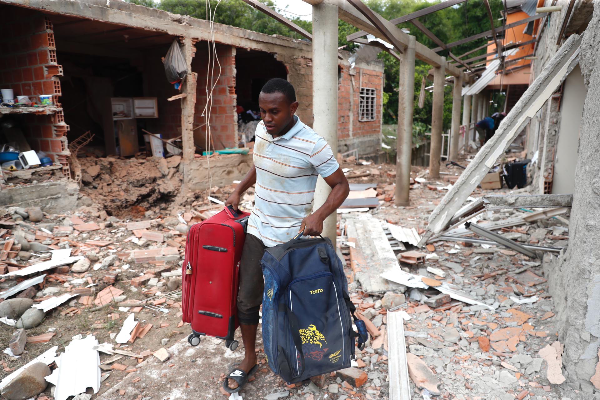 Un hombre camina con sus pertenencias frente a una casa afectada tras una explosión este 9 de octubre de 2025, en Robles, Jamundí (Colombia). EFE/ Ernesto Guzmán