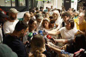 Activistas hacen declaraciones en la llegada este lunes al aeropuerto de Barajas, en Madrid, de otro grupo de españoles que integraban la flotilla Global Sumud, en un avión A-400 de la Fuerza Aérea Española. EFE/Juanjo Martín
