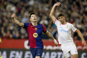 El delantero del FC Barcelona Robert Lewandowski (i) junto al sevillista Kike Salas, durante el encuentro de la jornada 23 de la pasada LaLiga EA Sports disputado en el Sánchez Pizjuán. EFE/ Julio Muñoz