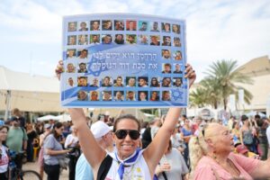 Una mujer sostiene un cartel con fotos de rehenes israelíes que dice en hebreo, 'El Misericordioso levantará para nosotros la tienda caída de David', durante una celebración después de que se anunció un acuerdo de paz en la Plaza de los Rehenes en Tel Aviv, Israel, 09 de octubre de 2025. El presidente de EE.UU., Donald Trump, anunció que Israel y Hamas han acordado la primera fase de un plan de paz para Gaza. El acuerdo incluye la liberación de rehenes israelíes y prisioneros palestinos, la retirada de las fuerzas israelíes y la entrega de ayuda humanitaria a Gaza. EFE/EPA/ABIR SULTAN