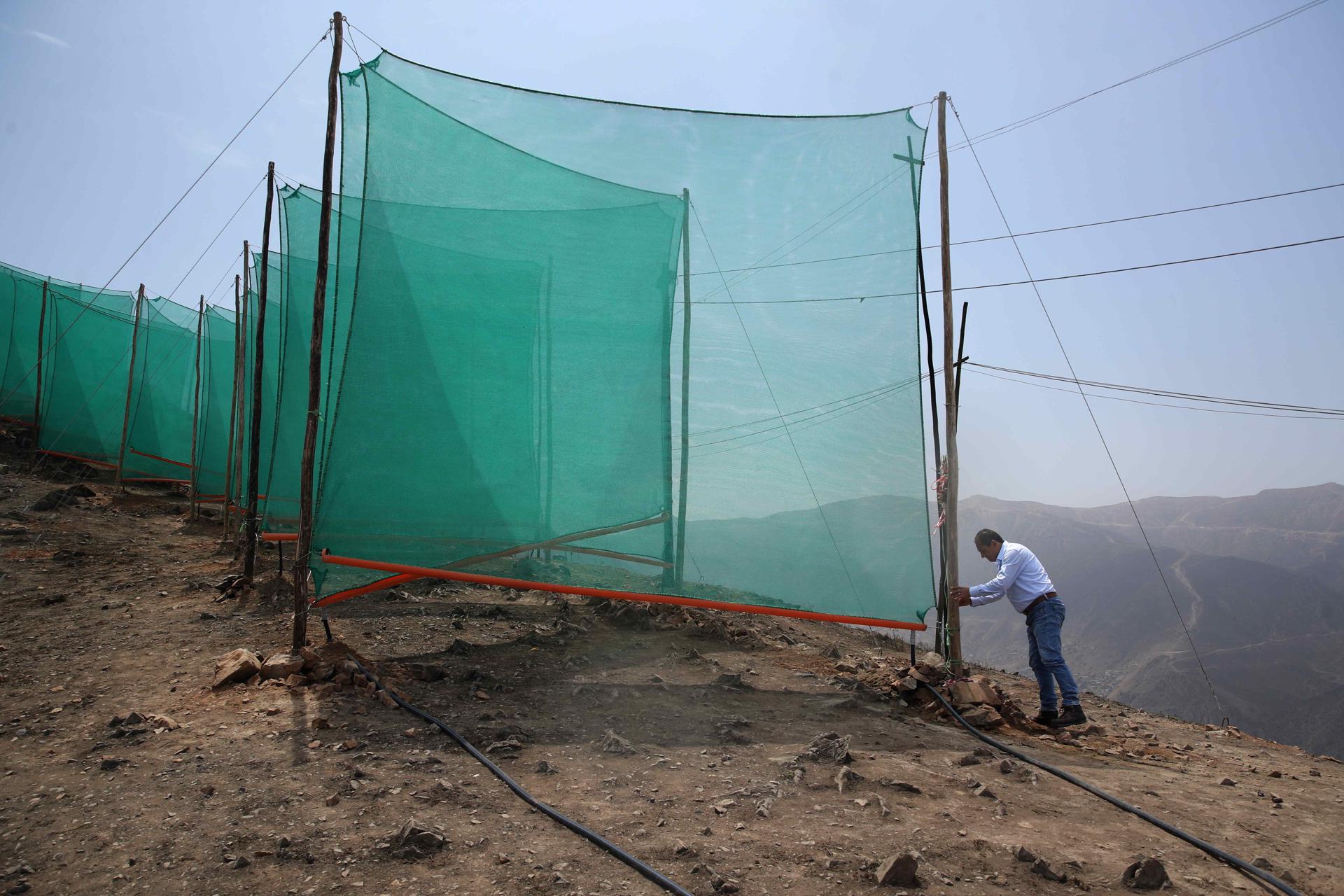 Un hombre revisando la estructura de un sistema de captación hídrica en los cerros de Lima (Perú). EFE/ Paolo Aguilar
