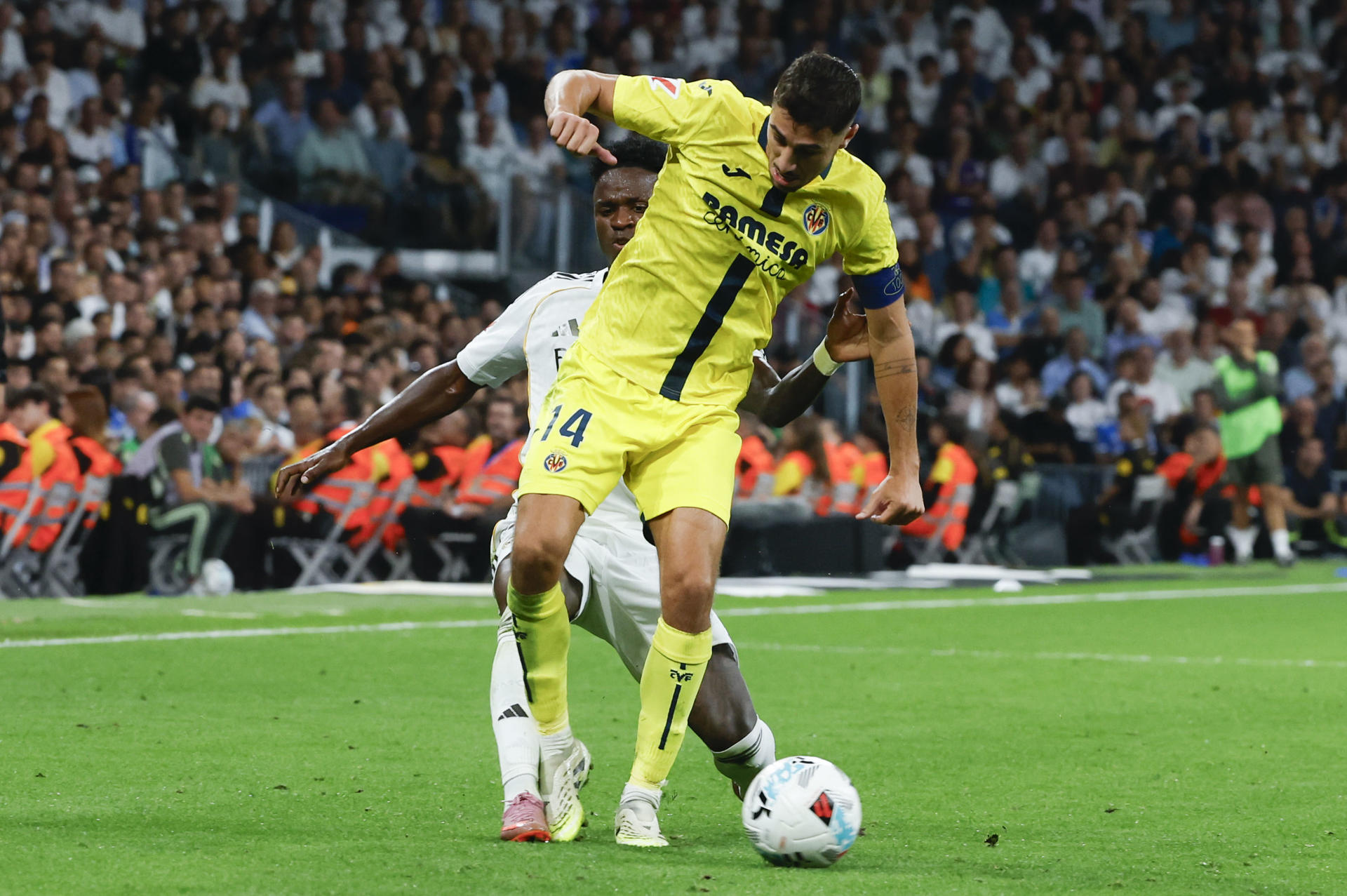 El centrocampista del Villarreal Santi Comesaña (d) juega un balón ante Vinicius Junior, del Real Madrid, durante el partido de LaLiga de fútbol que Real Madrid y Villarreal disputaron en el estadio Santiago Bernabéu. EFE/Guillén