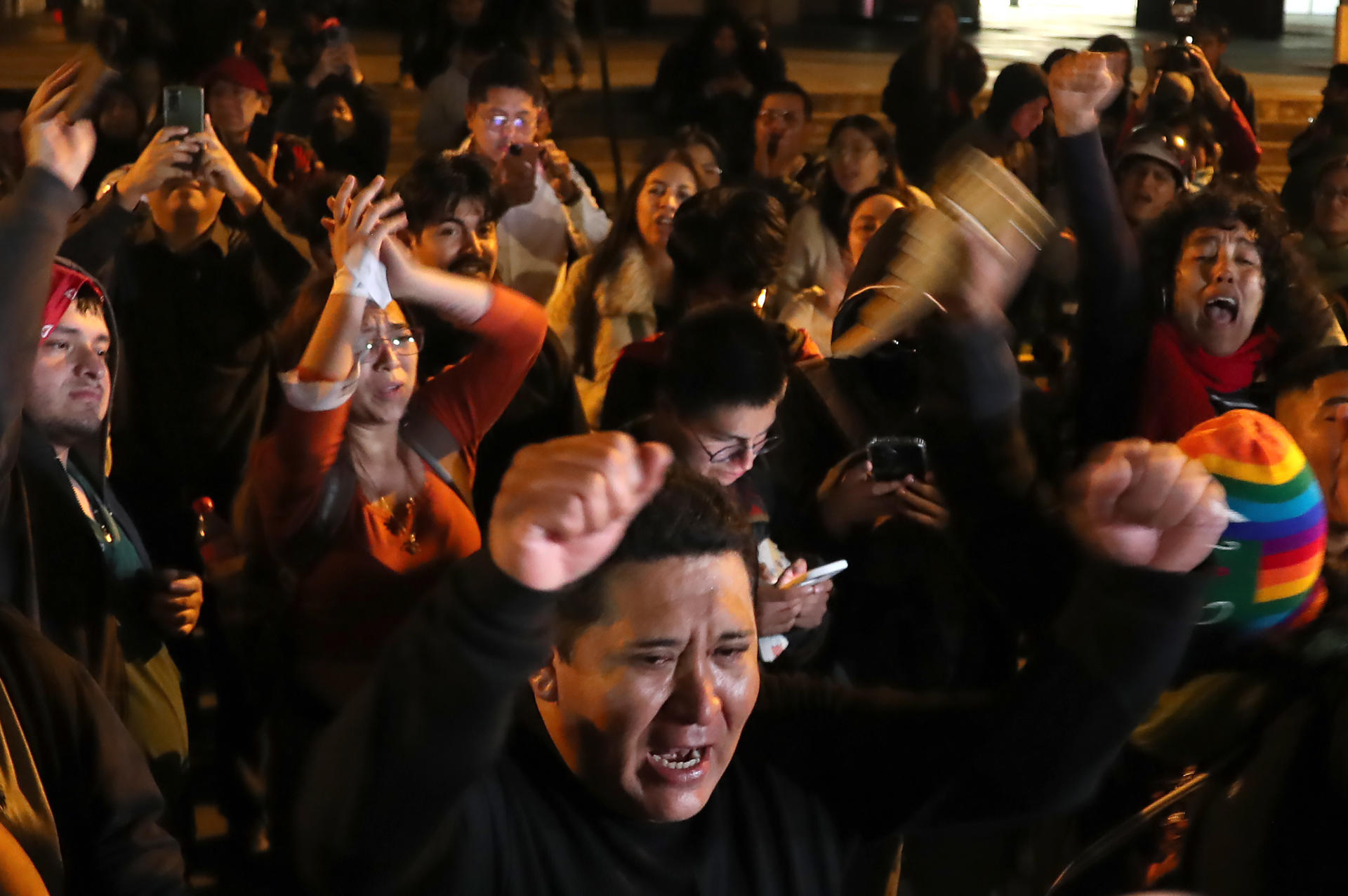 Peruanos celebran delante de la Embajada de Ecuador este jueves, en Lima (Perú). El Congreso de Perú destituyó de manera exprés a la presidenta, Dina Boluarte, tras aglutinar cuatro mociones de vacancia (destitución) para declarar su "permanente incapacidad moral" para enfrentar la creciente inseguridad ciudadana y el auge del crimen organizado, cuando faltan escasos seis meses para las elecciones generales de 2026.
EFE/ Paolo Aguilar