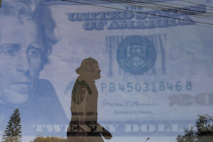 Fotografía de doble exposición que muestra un billete de dólar estadounidense y un hombre caminando frente a una casa de cambio en la ciudad de Guadalajara, en Jalisco (México). Imagen de archivo. EFE/ Francisco Guasco