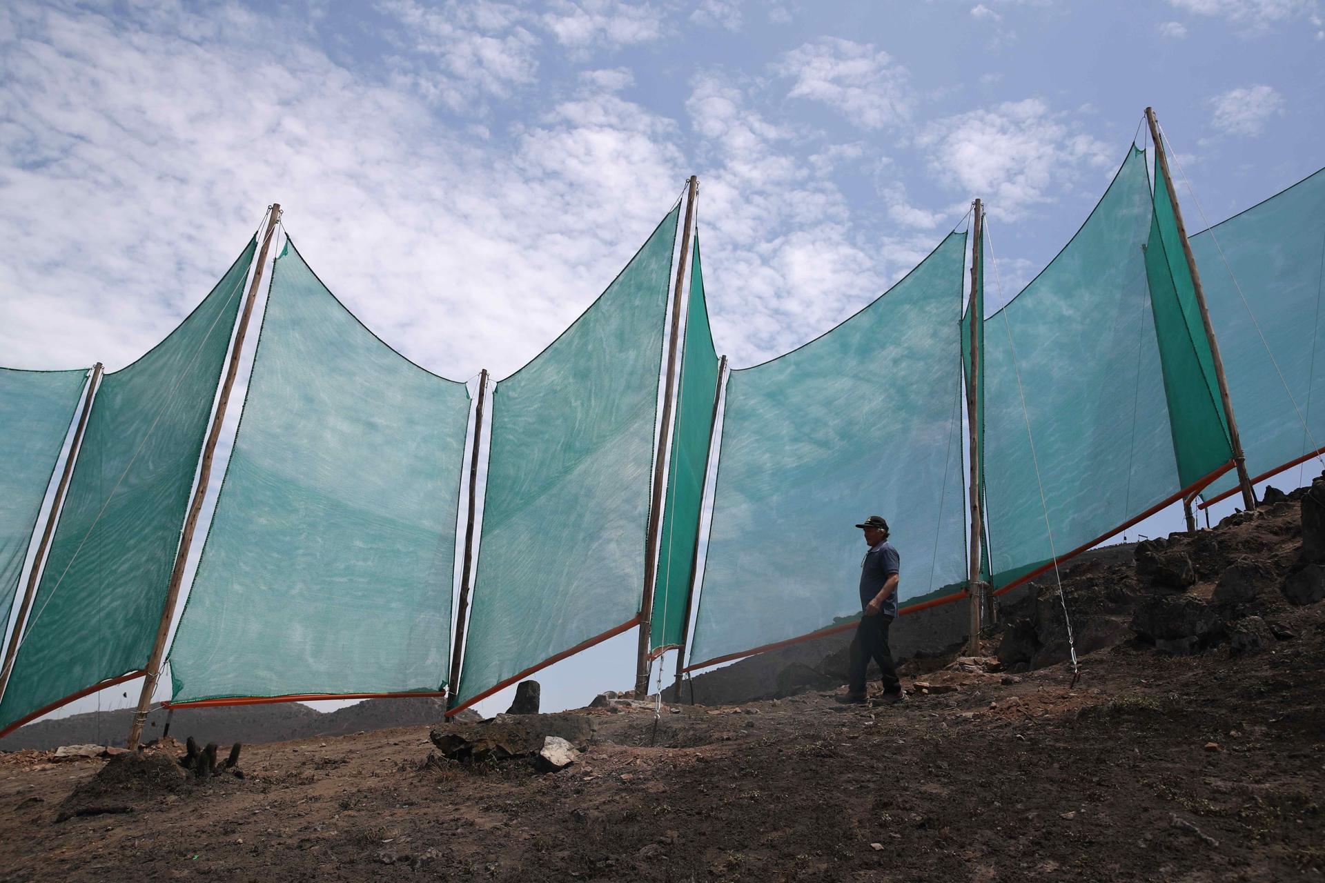 Un hombre revisando la estructura de un sistema de captación hídrica en los cerros de Lima (Perú). EFE/ Paolo Aguilar