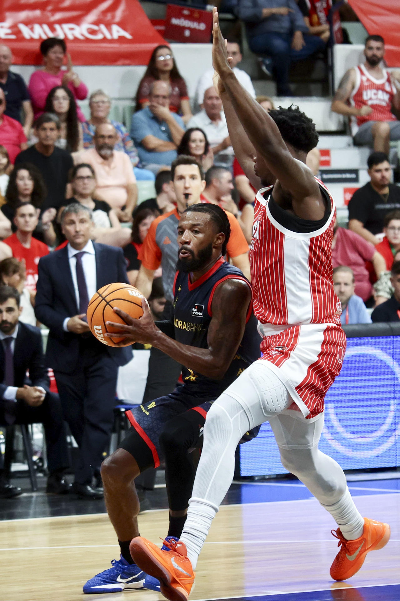 El base del Morabank Andorra Shannon Evans (i) con el balón ante Devontae Cacok, del UCAM Murcia durante el partido de Liga Endesa disputado ente el UCAM Murcia y el Morabank Andorra, este domingo en el Palacio de los Deportes de Murcia. EFE/ Juan Carlos Caval
