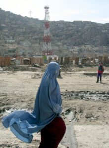 Una mujer afgana vestida con un burka pasa delante de una torre de comunicación de Kabul, Afganistán, en una imagen de archivo. EFE/SYED JAN SABAWOON