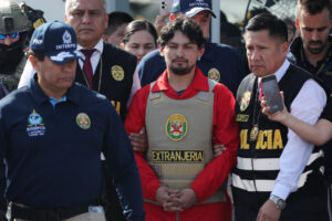 Matías Agustín Ozorio (c), de nacionalidad argentina, es trasladado por integrantes de la Policía Nacional de Perú (PNP) y de Interpol para ser entregado a la Policía Argentina este jueves, en la Base Aérea de Policía Aérea de Perú en Lima (Perú). EFE/ Paolo Aguilar