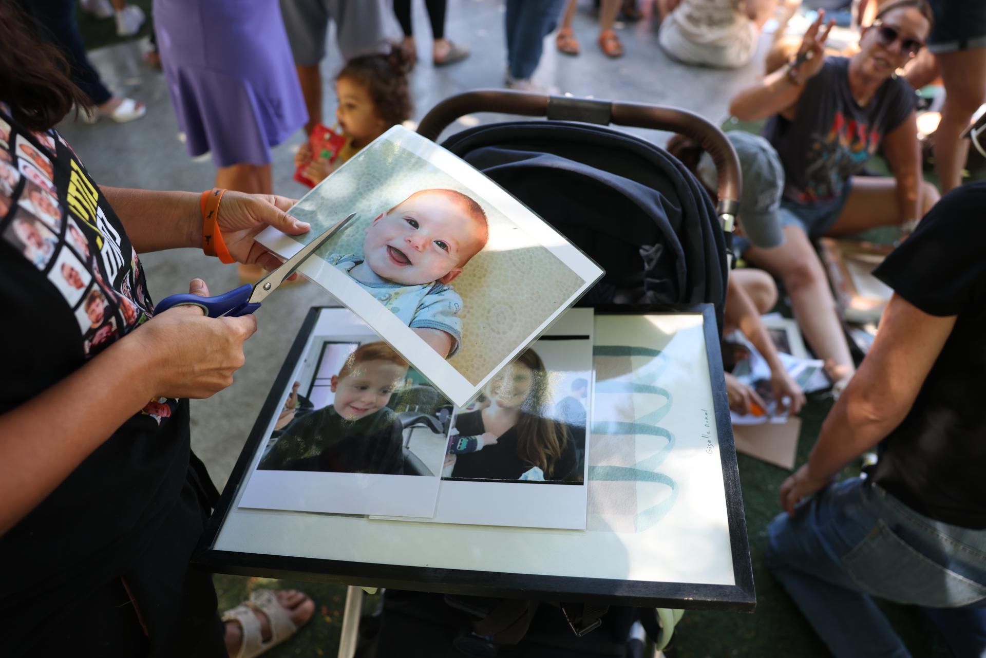 Personas colocando fotos de víctimas israelíes del ataque del 7 de octubre en la fuente de la plaza Dizengoff en Tel Aviv, Israel. EFE/ABIR SULTAN
