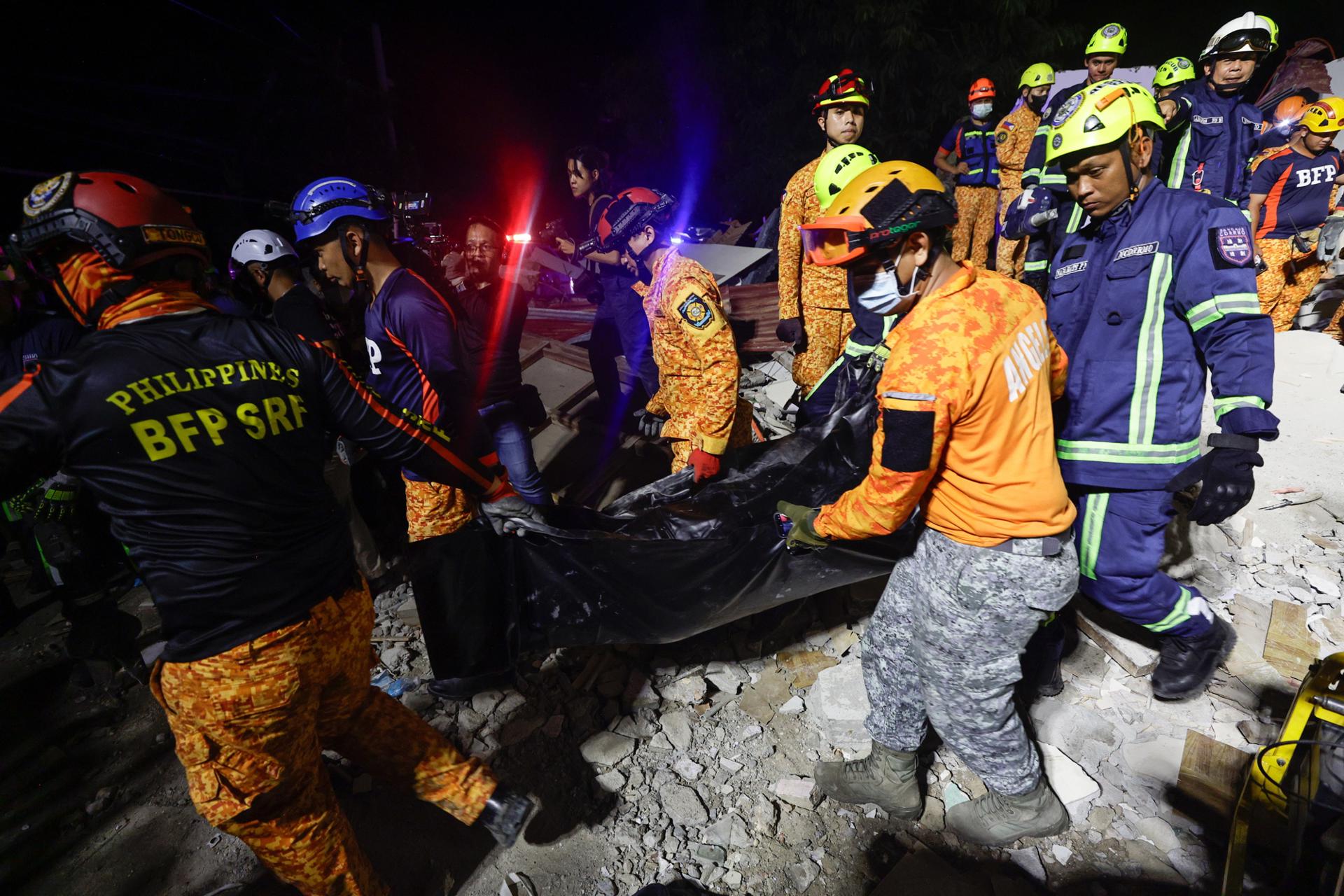 Rescatistas fueron captados este miércoles, 1 de octubre, al recuperar el cuerpo de una víctima del terremoto de magnitud 6.9 que en la víspera azotó el centro de Filipinas, en una instalación colapsada en la ciudad de Bogo. EFE/Rolex de la Pena