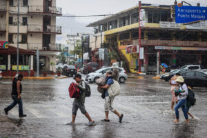 Personas caminan por una calle encharcada debido a las fuertes lluvias en el balneario de Acapulco, estado de Guerrero (México). Imagen de archivo. EFE/David Guzmán