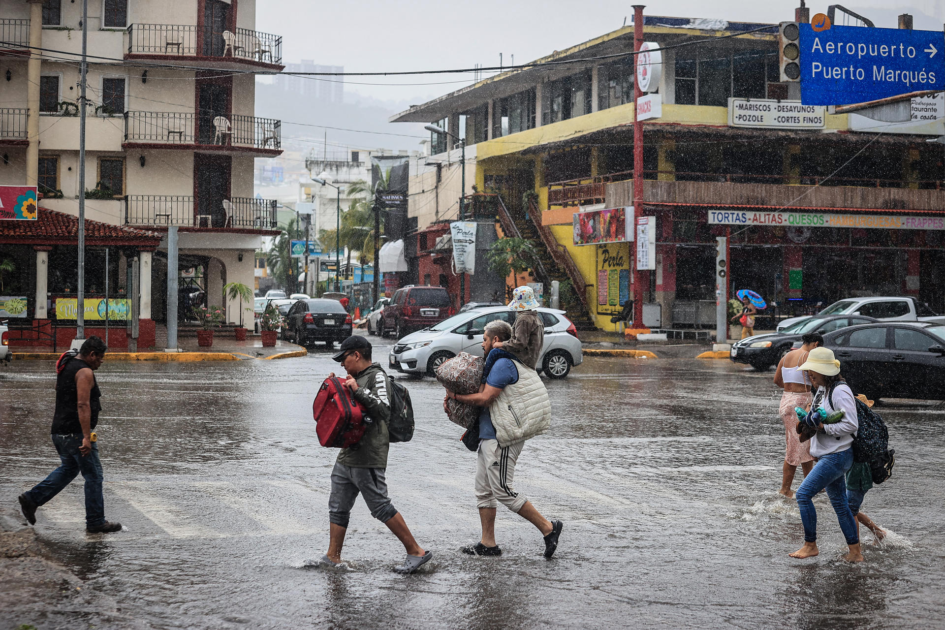 Personas caminan por una calle encharcada debido a las fuertes lluvias en el balneario de Acapulco, estado de Guerrero (México). Imagen de archivo. EFE/David Guzmán