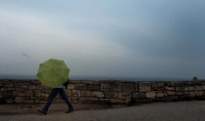 Una mujer camina con un paraguas durante una tormenta en Kaliakra, a unos 500 kilómetros de Sofía (Bulgaria). EFE/Vassil Donev