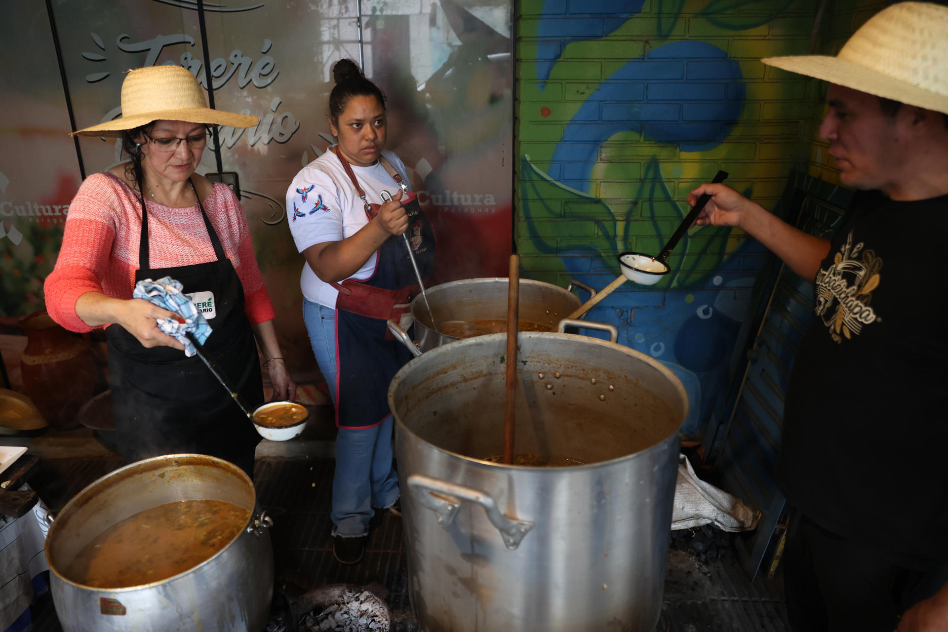 Personas preparan una sopa de vegetales, frijoles y maíz, durante la celebración del jopará este miércoles, en el Mercado 4 en Asunción (Paraguay). EFE/ Juan Pablo Pino