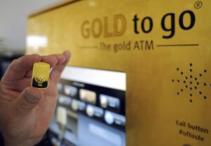 Un hombre sostiene una barra de oro de 10 gramos adquirido en una maquina de venta del metal preciado en el aeropuerto de Bremen. EFE/INGO WAGNER