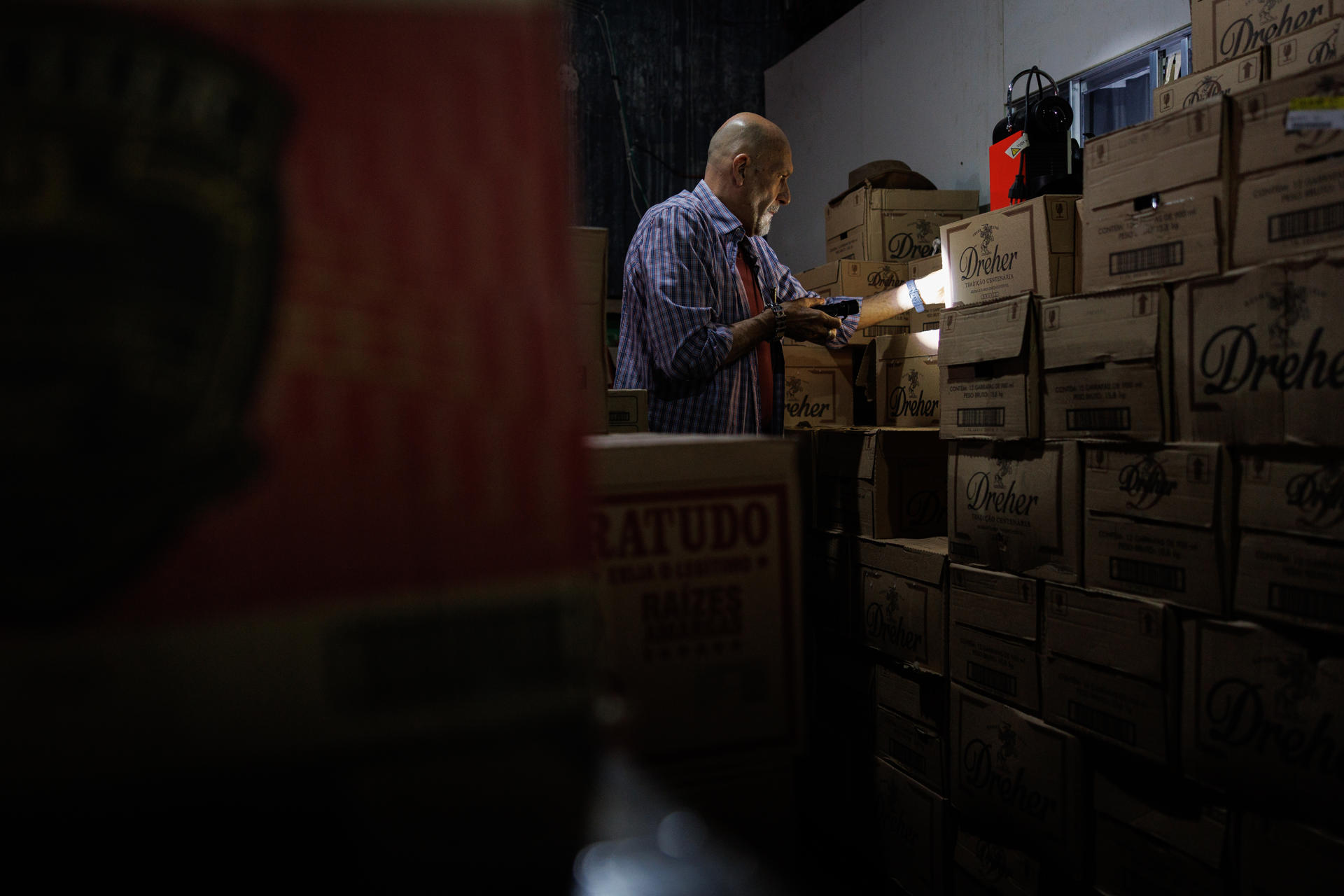 Un policía civil fue captado el pasado 2 de octubre al detallar algunas cajas de licor, durante un operativo para frenar los casos de intoxicación por bebidas adulteradas con metanol, en una bodega de la zona sur de São Paulo (Brasil). EFE/Isaac Fontana